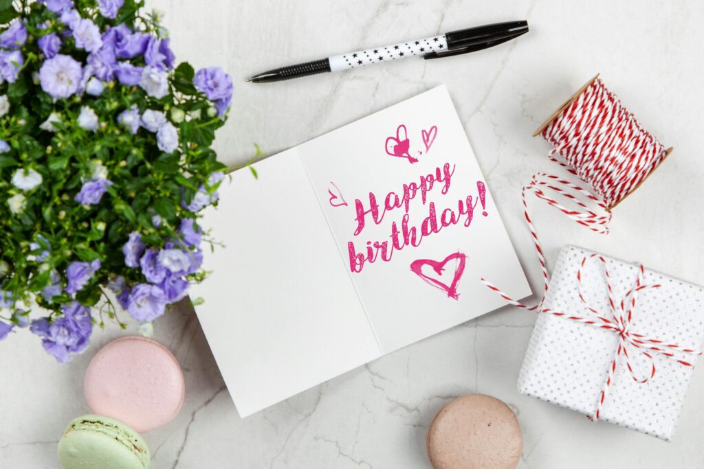 Charming birthday greeting card layout with macarons, flowers, and gift box.